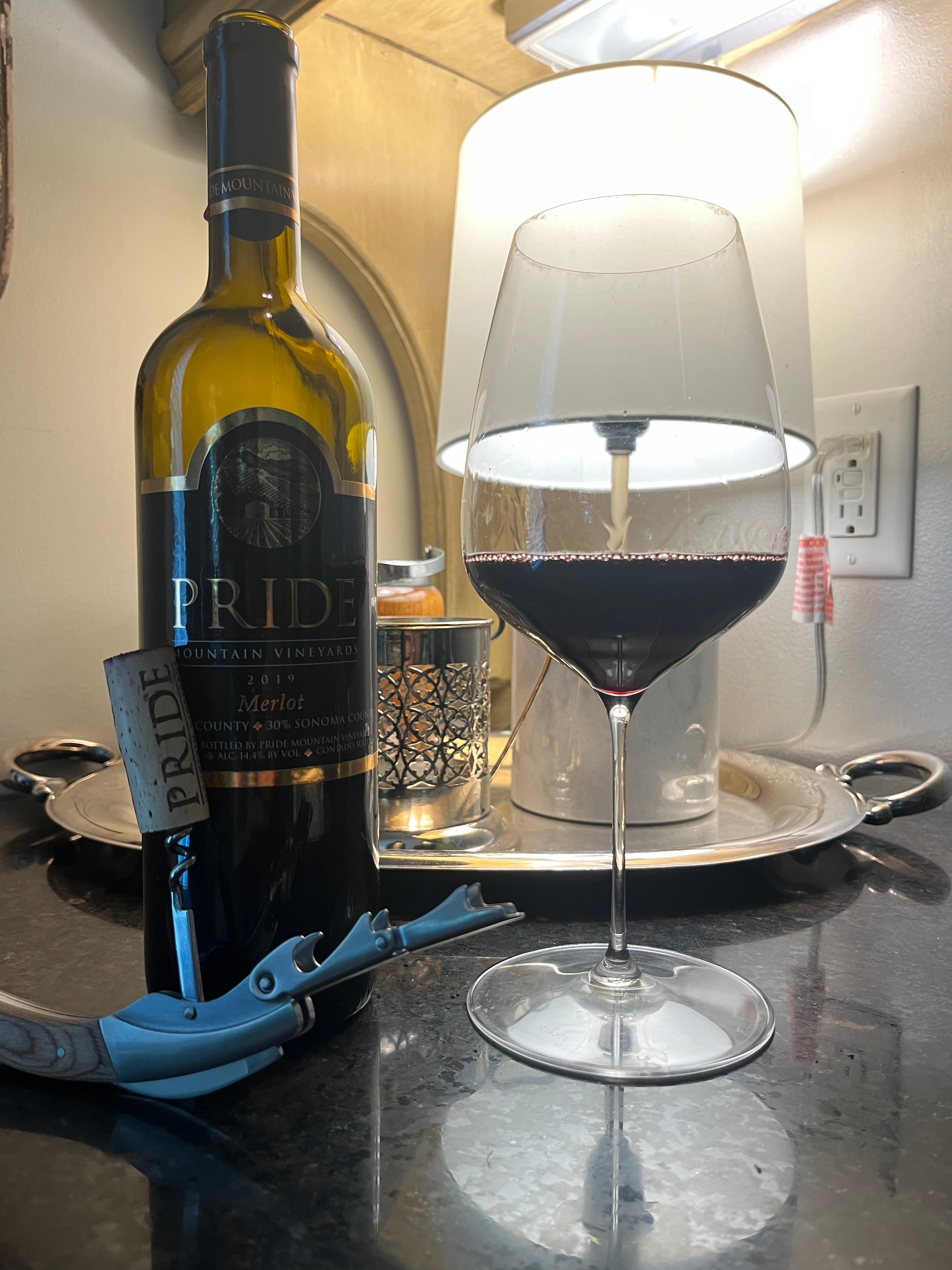 A bottle of red wine with a poured glass on a table